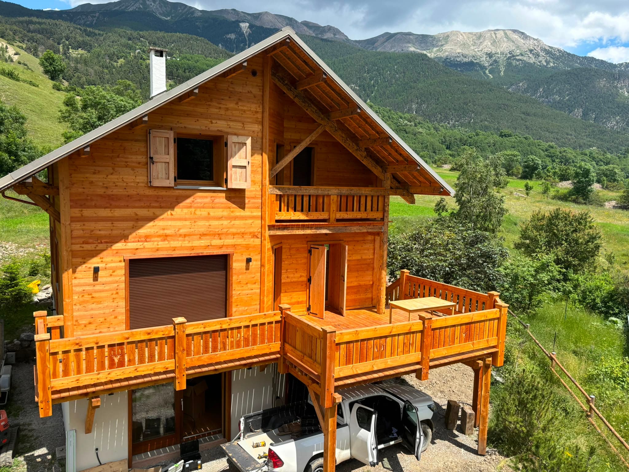 Vue aérienne d'un chalet en bois terminé, entouré de montagnes