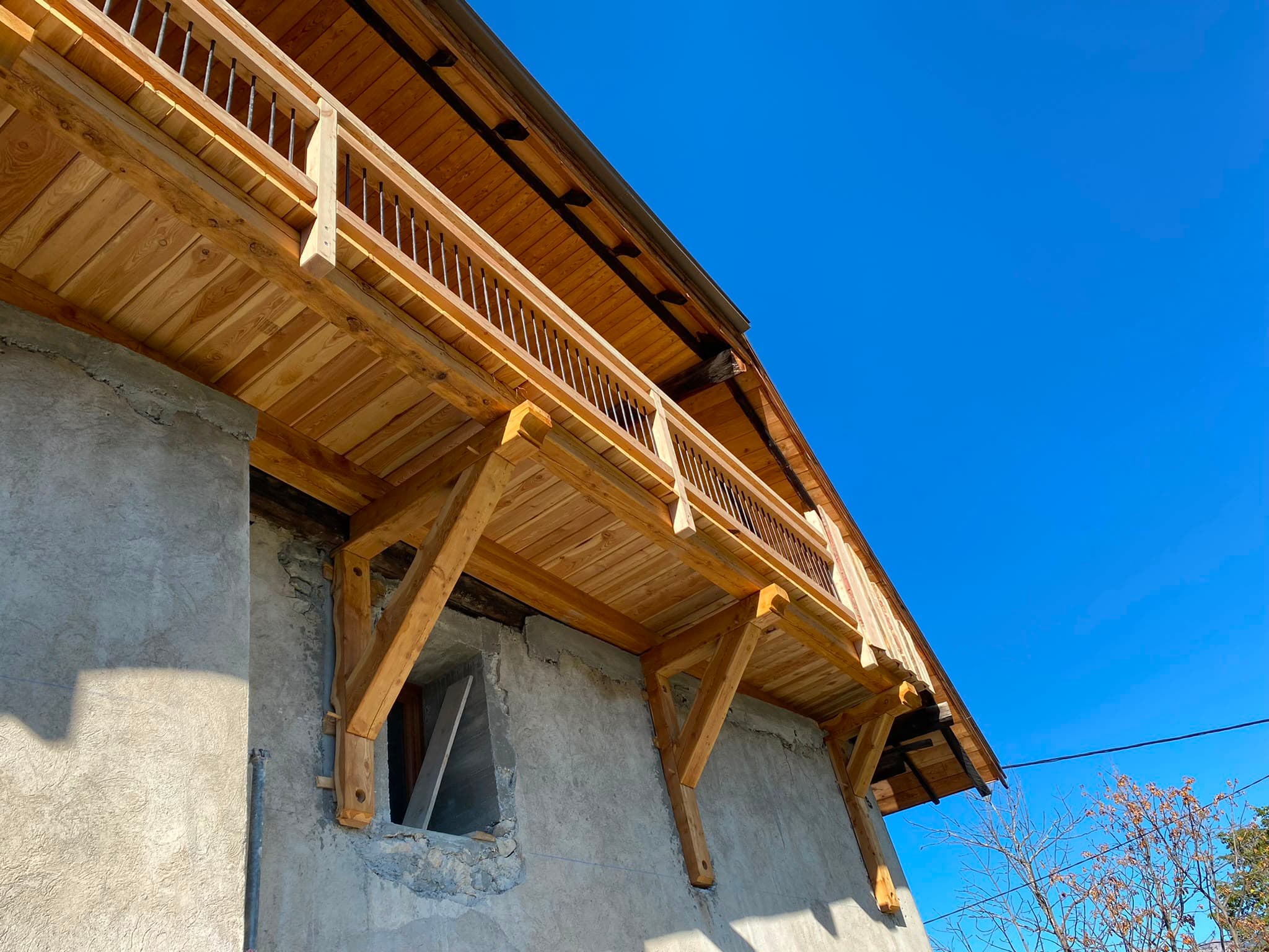 Balcon en bois et charpente en cours de finition, vue en contre-plongée