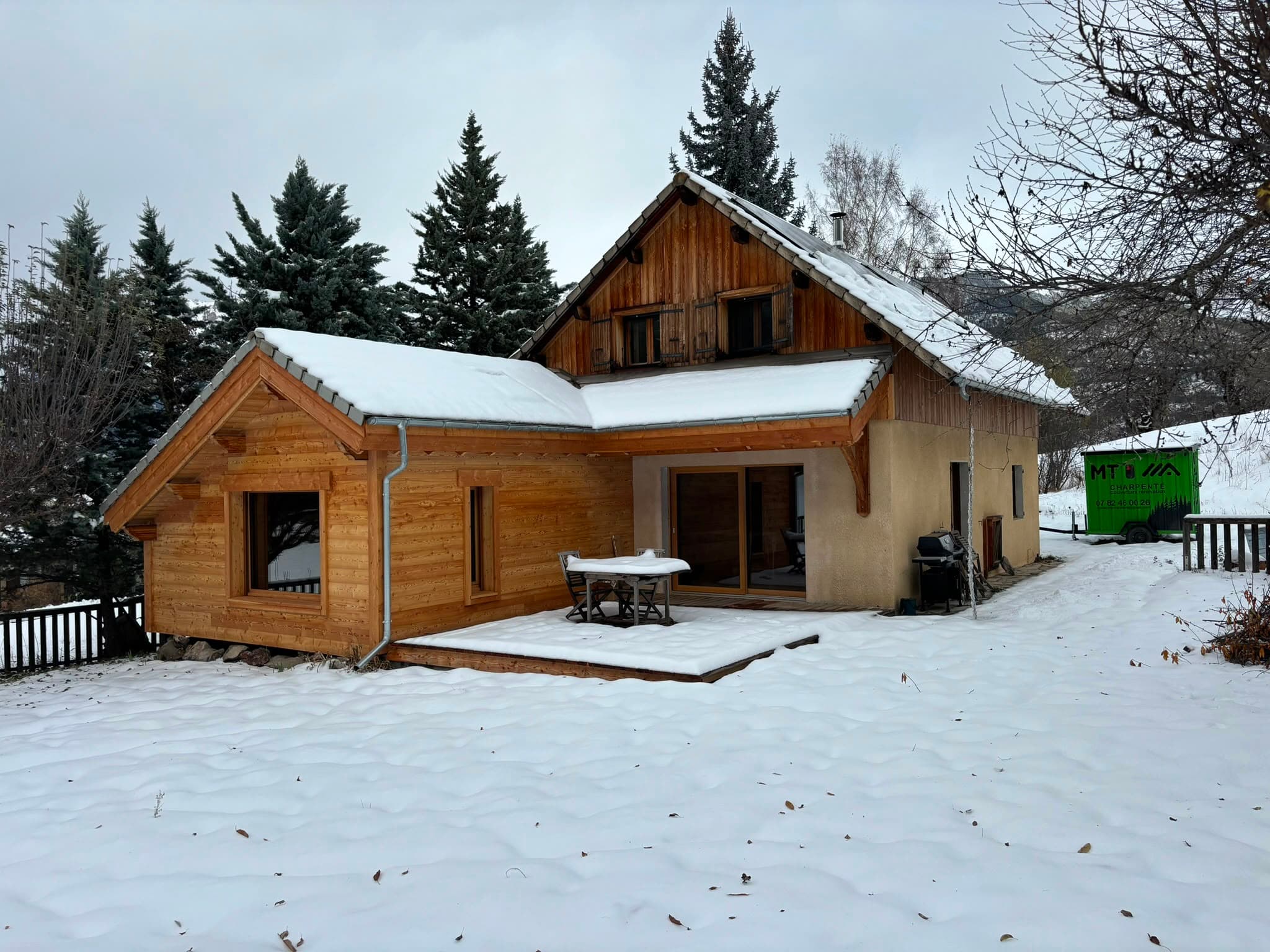 Chalet en bois sous la neige avec la remorque de chantier MT Charpente