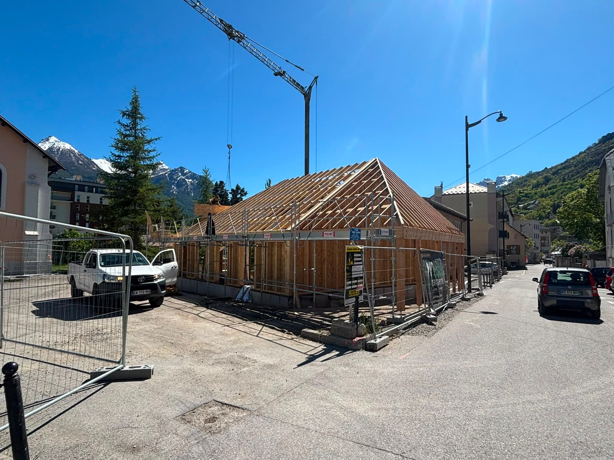 Charpente à fermes en bois en cours de montage, vue sur la vallée